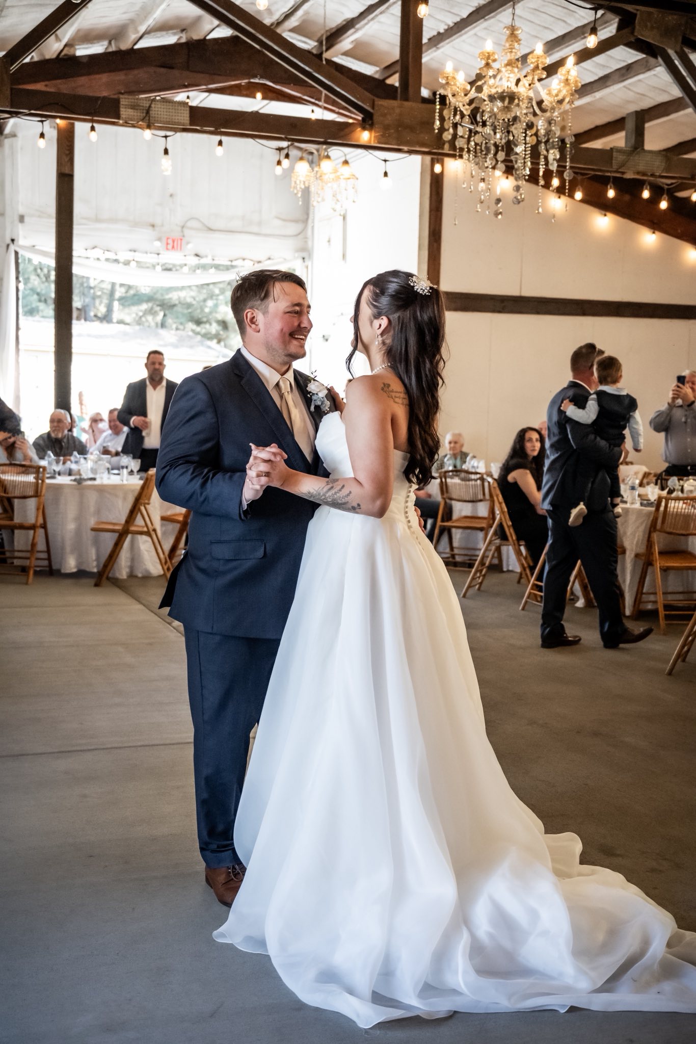 Newlyweds sharing their first dance beneath the chandeliers in the Stone Ridge barn