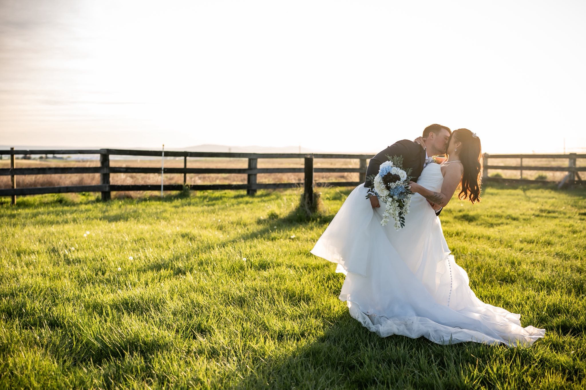 Newlyweds kissing in the pasture at golden hour at Stone Ridge Estates