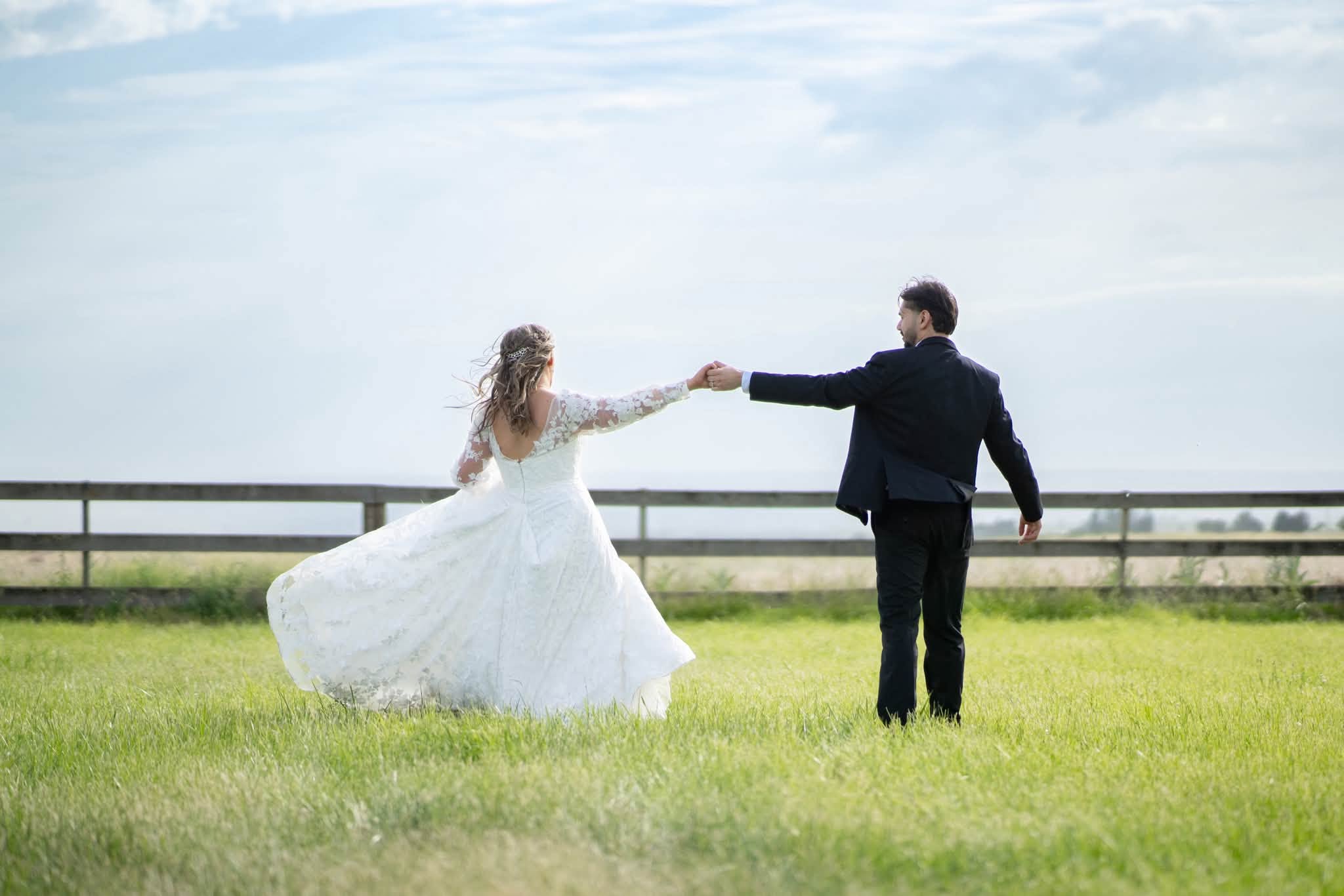 Newlyweds twirling together in the open pasture at Stone Ridge Estates