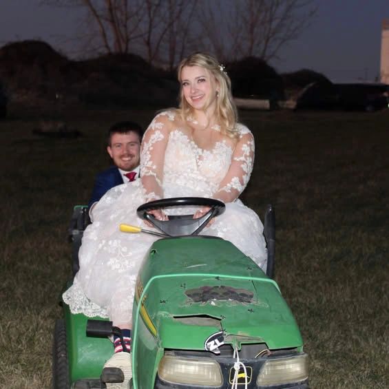 Newlyweds enjoying a playful tractor ride at Stone Ridge Estates